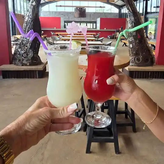 Two people hold up cocktails to toast each other.